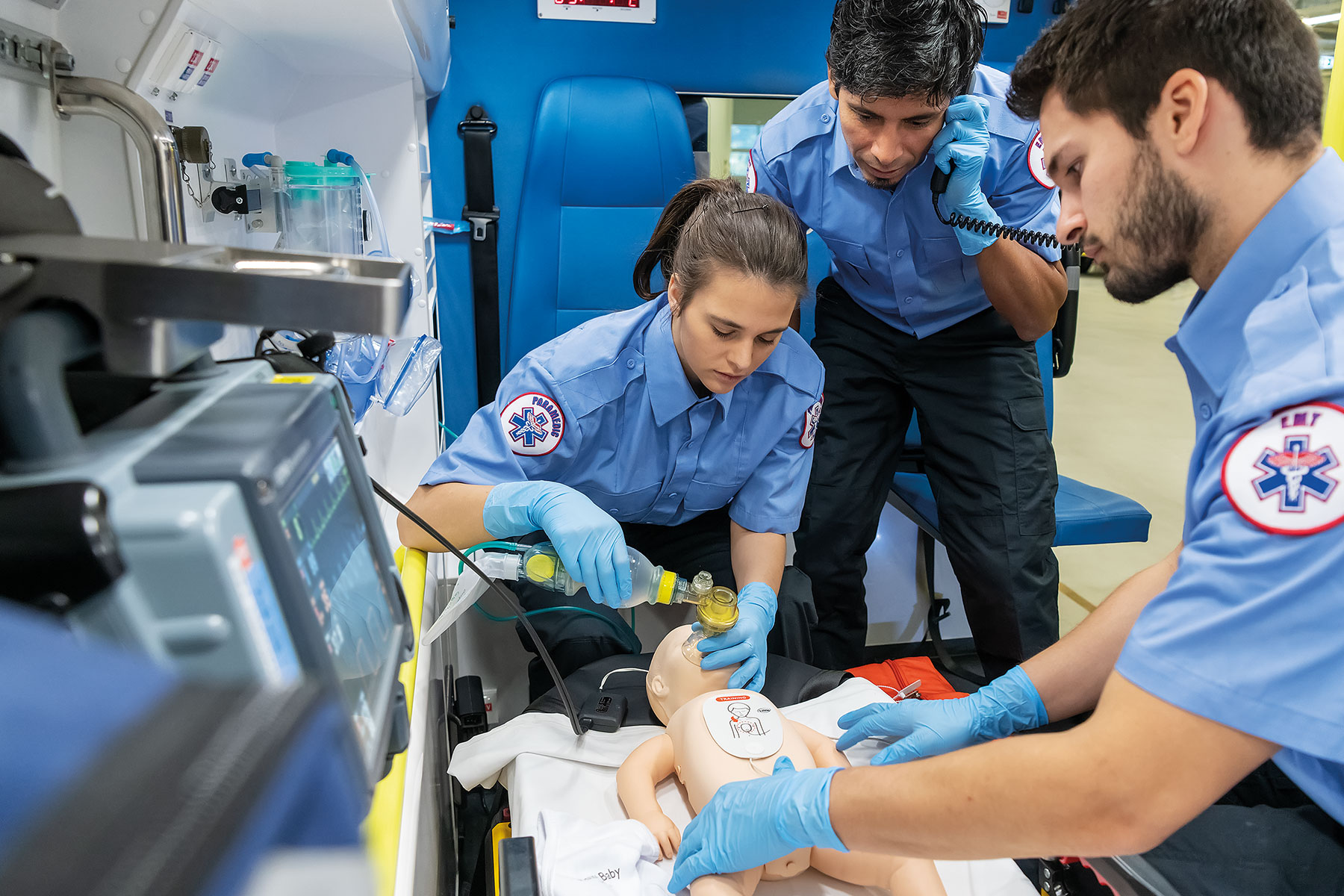 EMS team performing resuscitation on baby manikin inside of an amublance