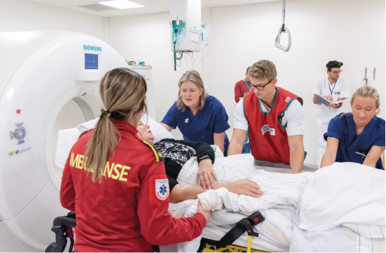 ambulance and hospital personnel helping a patient out of an MRI scanner inside a white hospital room