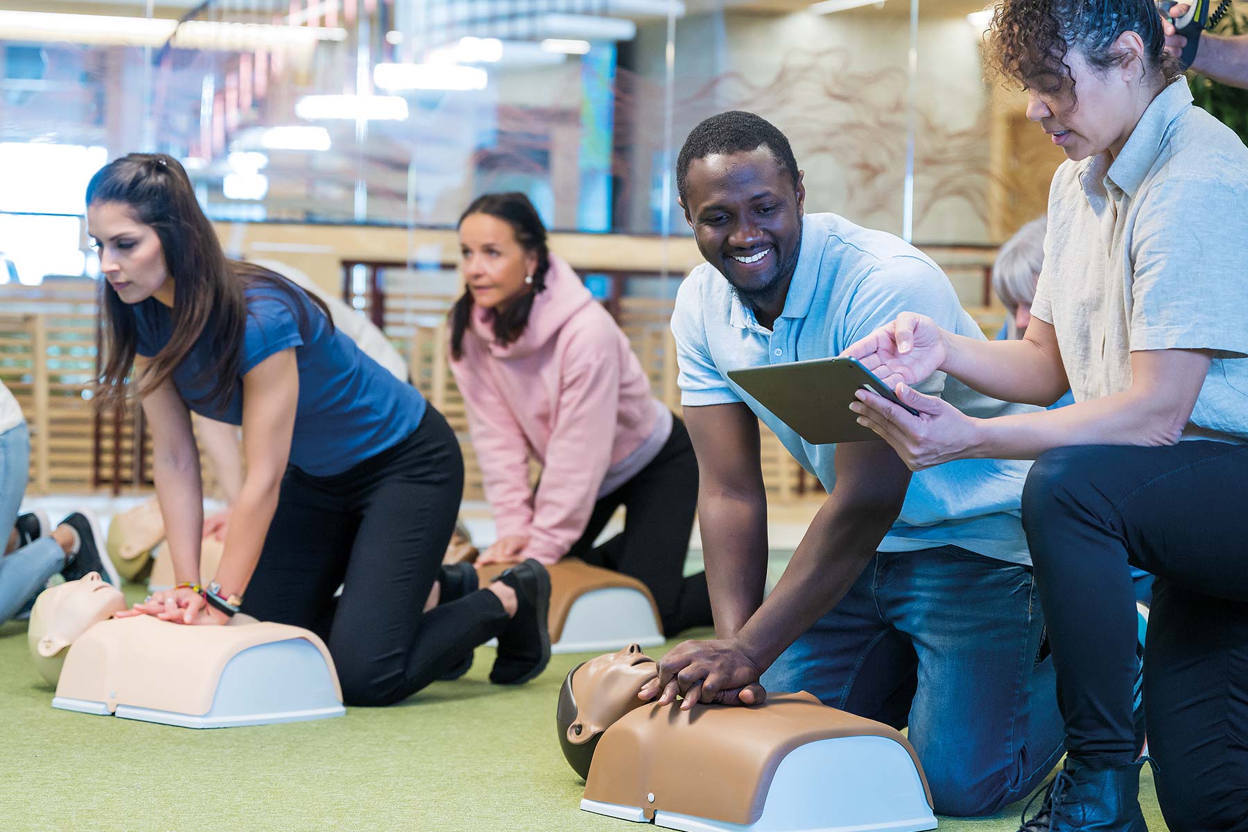 A group of individuals practicing CPR on several Little Anne torso training manikins