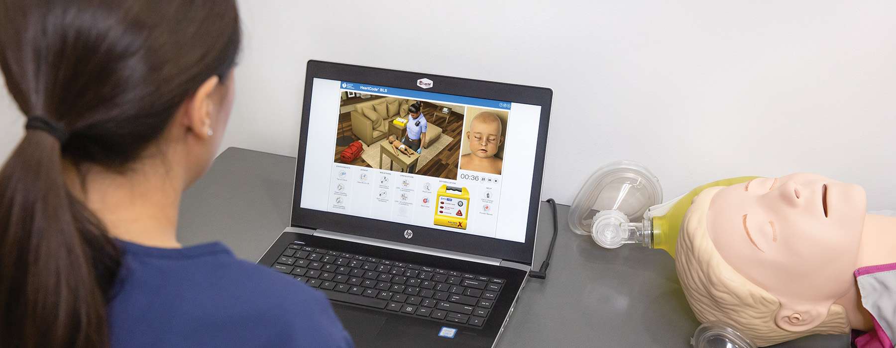 A student uses an interactive e-learning platform to complete Basic Life Support (BLS) training alongside a resuscitation manikin.