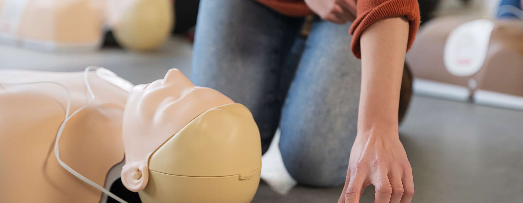 A close-up of a student preparing an adult CPR manikin for a training session.