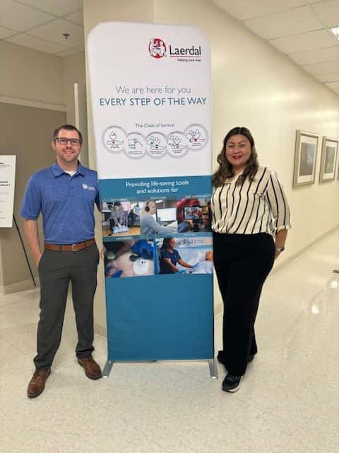 Jennifer and Brent standing in front of a Laerdal sign