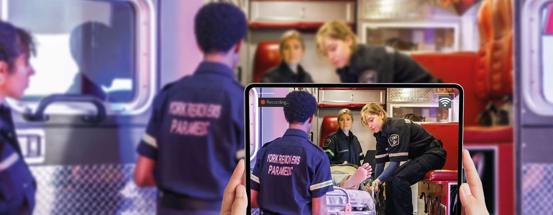 A hand-held tablet recording a simulation inside an ambulance, demonstrating mobile video capture for training debriefing.
