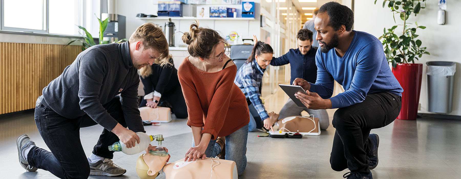 A group of trainees practice CPR, guided by an instructor using a digital feedback tablet.