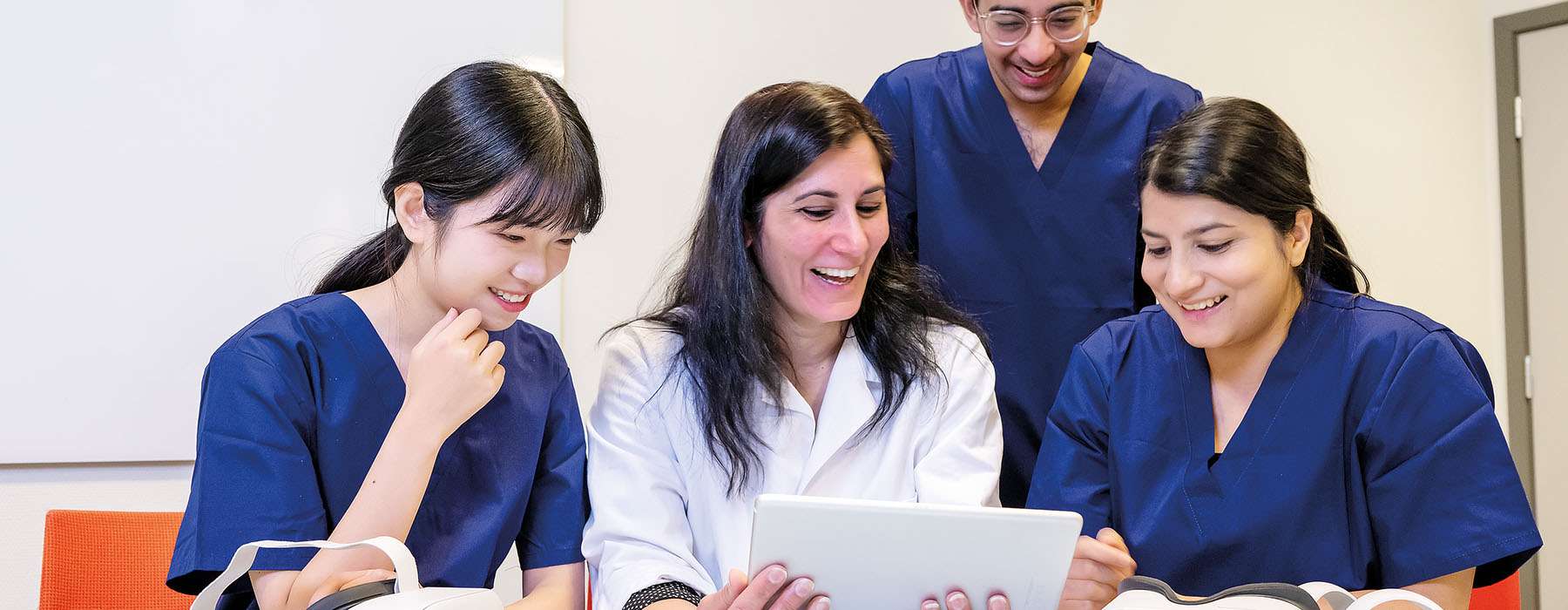 A clinical instructor and a group of nursing students collaborating on a tablet.
