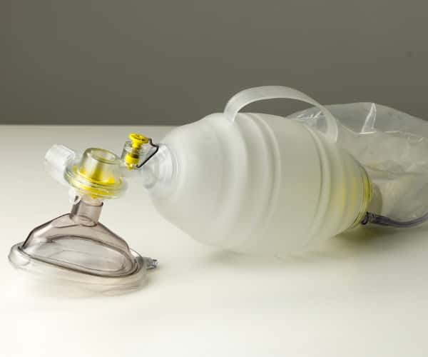 Manual resuscitator and oxygen mask placed on table