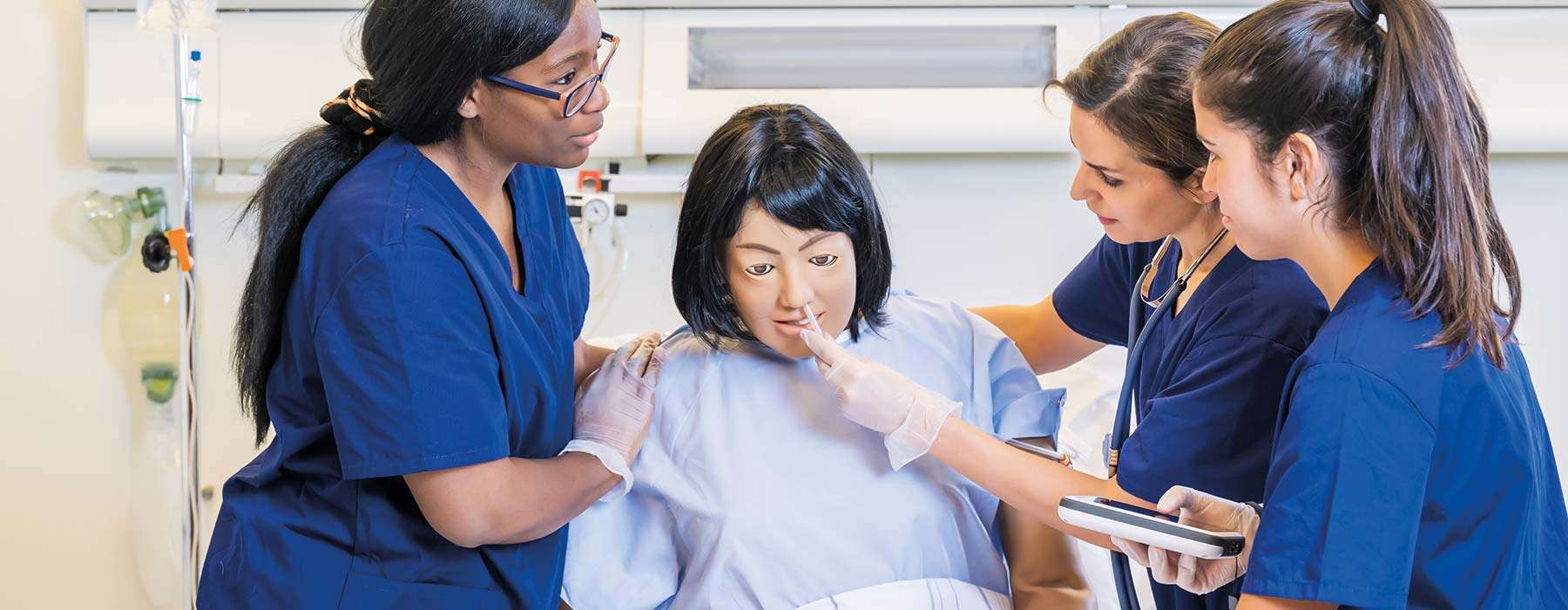 Nurses using NG tube and simpad on nursing anne simulator manikin
