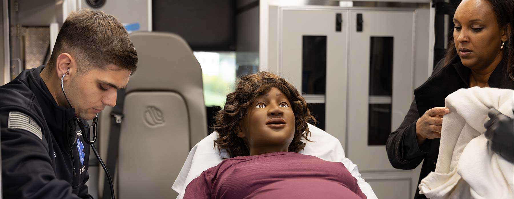 two paramedics checking blood pressure mamaanne simulator