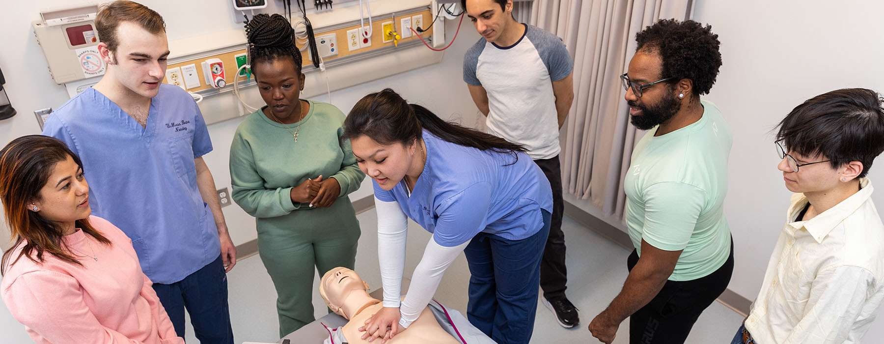 Group of nursing students attending a CPR group training session using a manikin. 