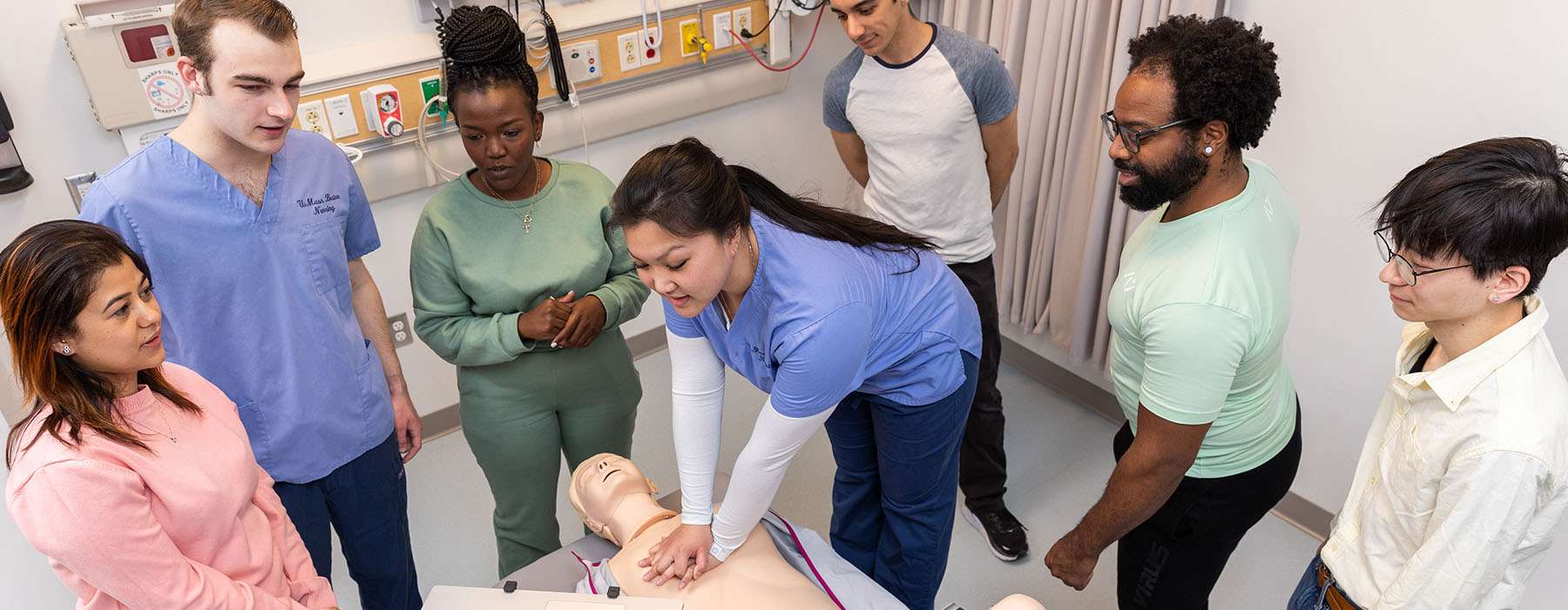 A team watching as a healthcare worker performs CPR on a baby manikin.