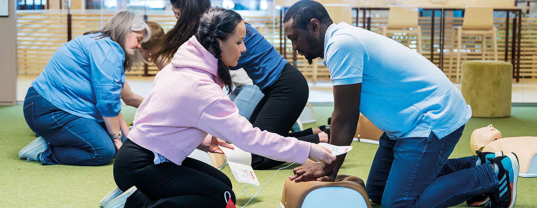 Group of people attending a CPR training session, using manikins to practice CPR