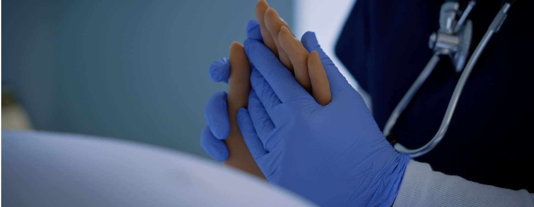 Gloved health worker holds MamaAnne hand