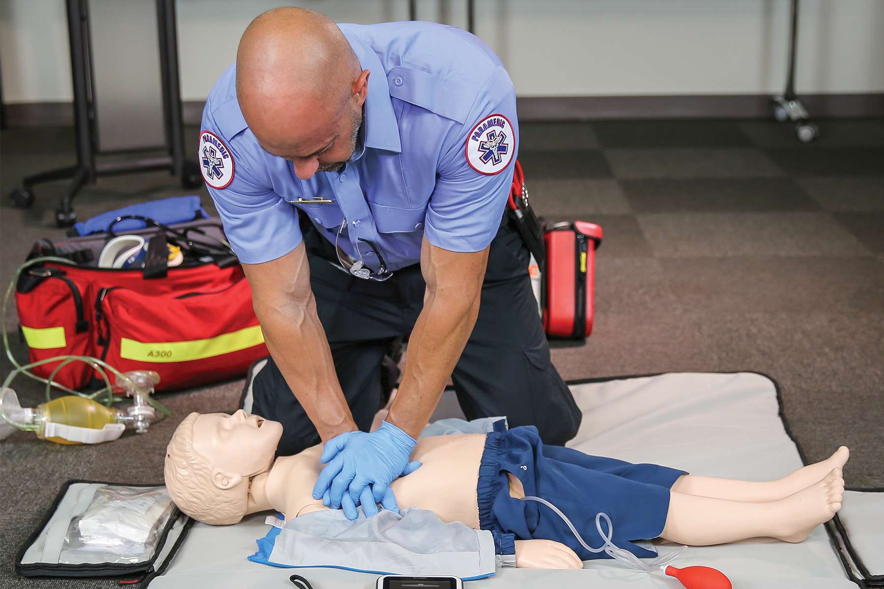 EMS worker doing CPR simulation training on Resusci Junior QCPR manikin