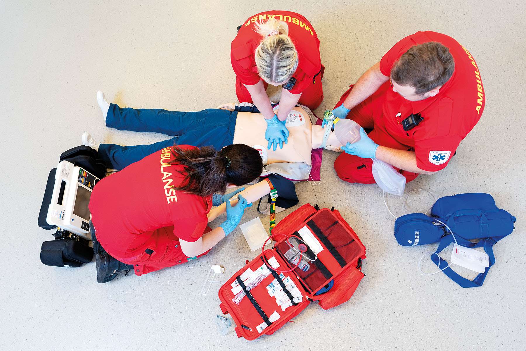 overhead view of 3 EMS workers doing simulation training on manikin