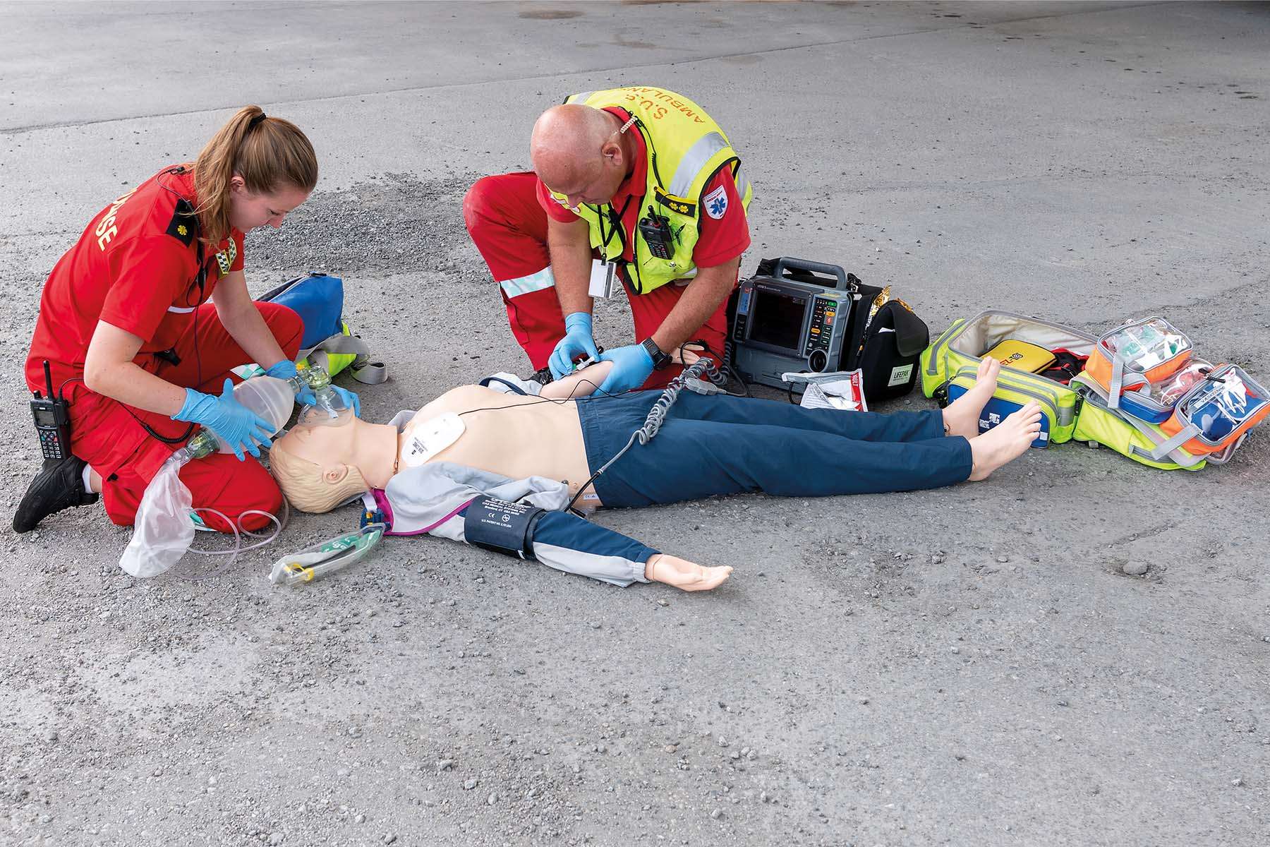Two EMS workers working on CPR simulation on manikin outside