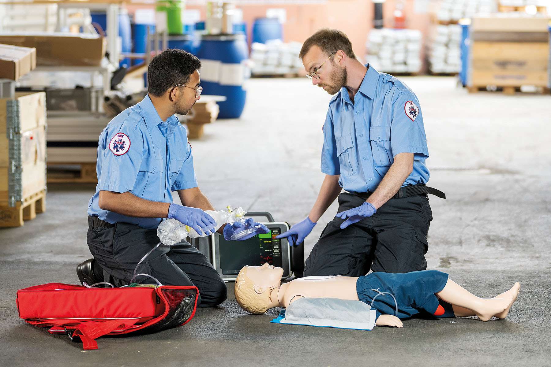Two EMS workers in outside environment working on simulation on Resusci Junior QCPR manikin and Monitor by Laerdal