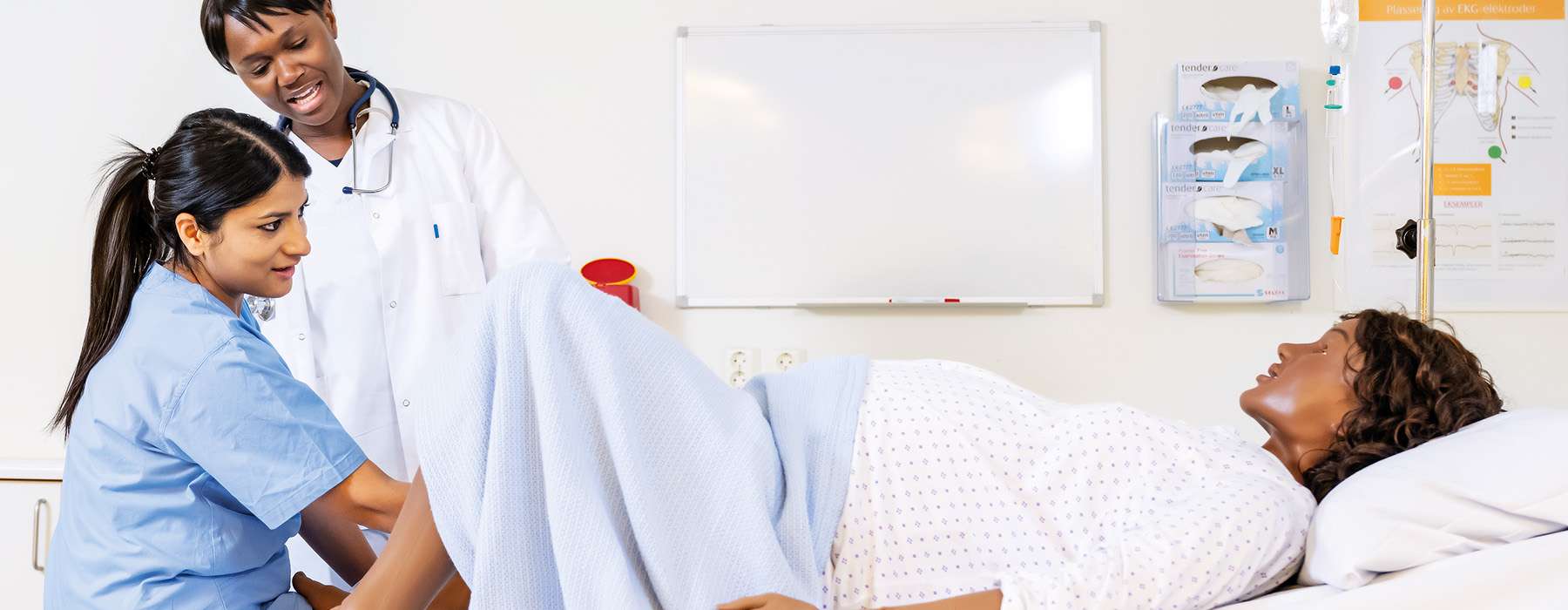Two healthcare professionals attending to a pregnant patient simulator (mannequin) during a medical or simulation training session.