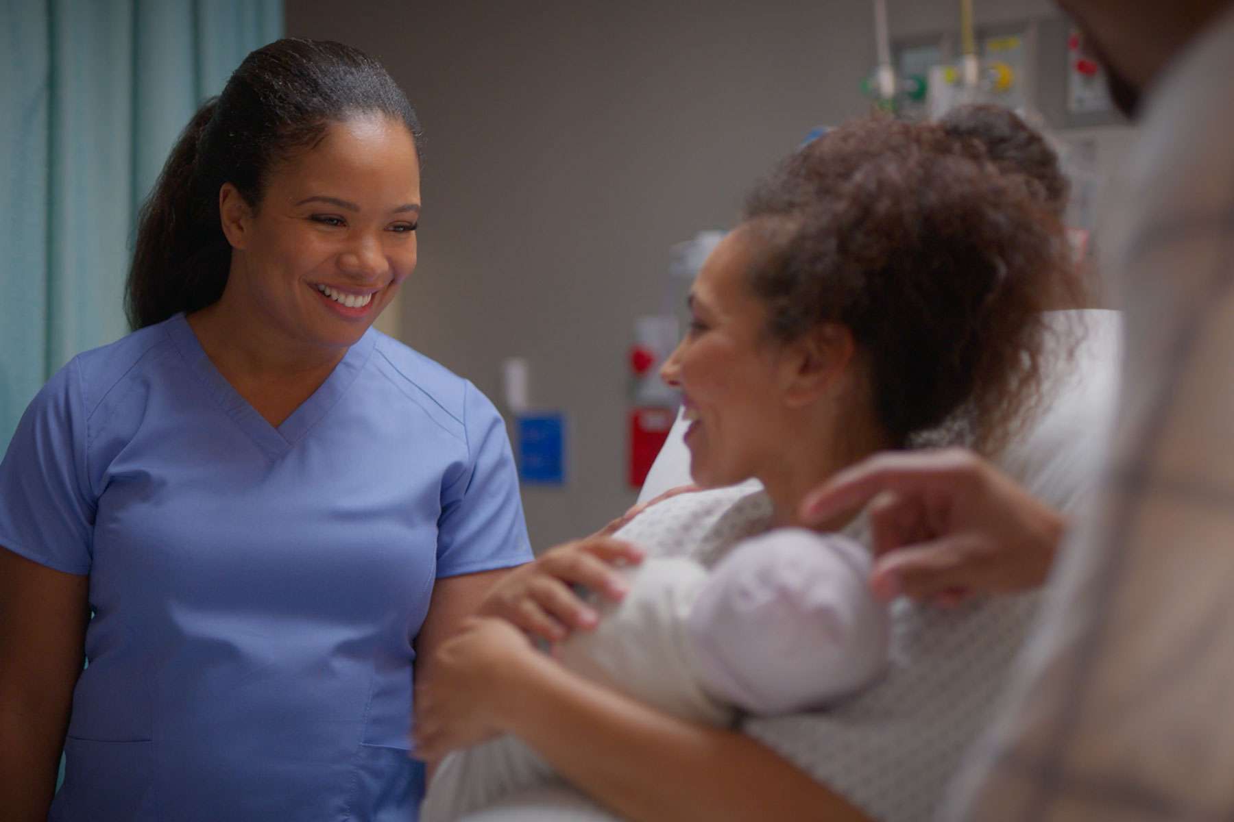nurse smiling at mother holding newborn